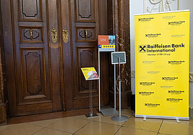 "Foto von Holztür mit Ständer mit Logos der Raiffeisenbank.