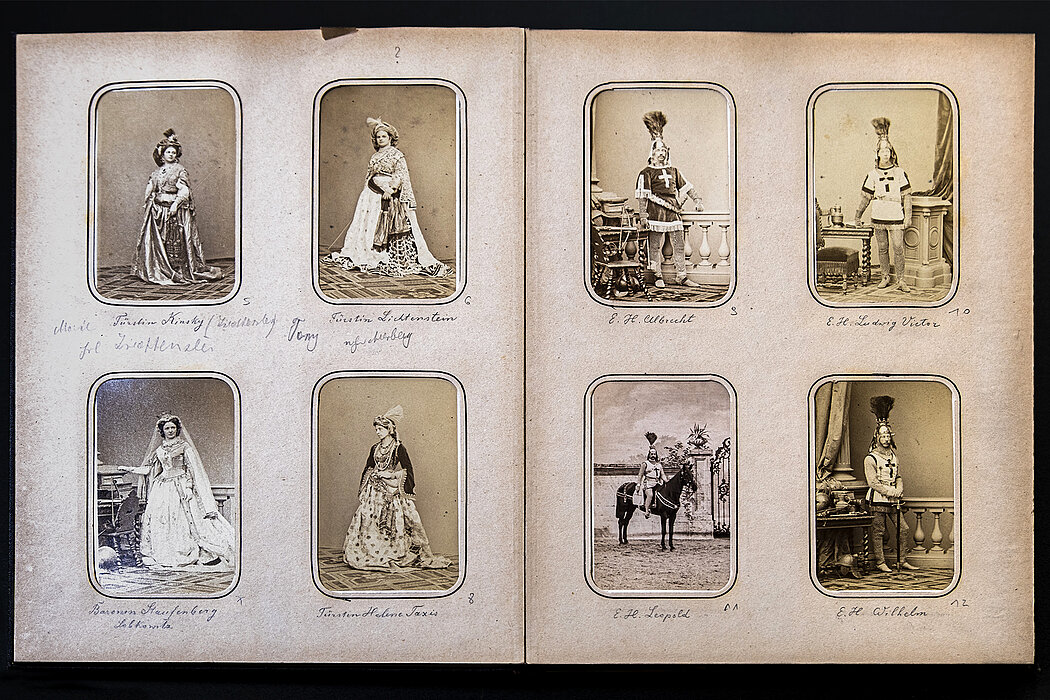 Aufgeschlagenes Album mit schwarz-weißen Fotos von Menschen in Kostümen.