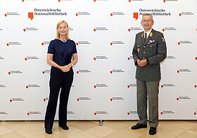 Zwei Personen posieren vor einer Logowand.