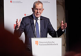 Person im Anzug am Rednerpult. 