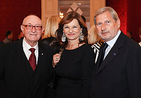 Drei elegant gekleidete Personen posieren stehend.