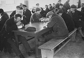 Bedürftige sitzen an einem Tisch und essen