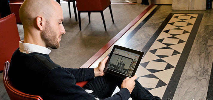 Ein Mann mit Tablet sitzt in der Kommunikationslounge der Lesesäle am Heldenplatz