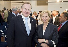 Eine Person im Anzug und eine Person mit dunklem Blazer. Im Hintergrund viele Menschen.