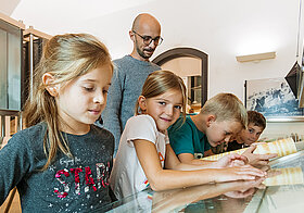 Children are looking at a display case in the Papyrus Museum of the Austrian National Library during a guided tour.