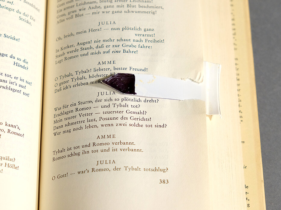 Buchseite von Theaterstück mit Plastikpfeil markiert