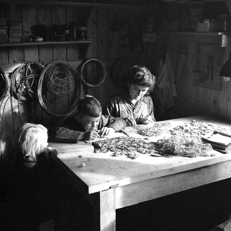 Familie bei der Glasperlenkettenerzeugung in Heimarbeit, Schwarz-weiß-Fotografie