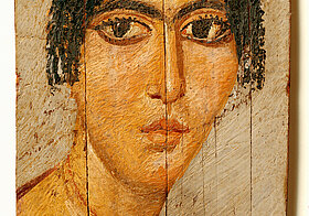 Zeichnung einer Person mit dunklen Haaren und braunen Gewändern auf Papyrus.