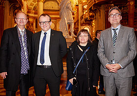Vier Personen in eleganter Kleidung im Prunksaal.