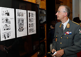 Person im Militär-Anzug blickt auf Storyboards im Literaturmuseum.