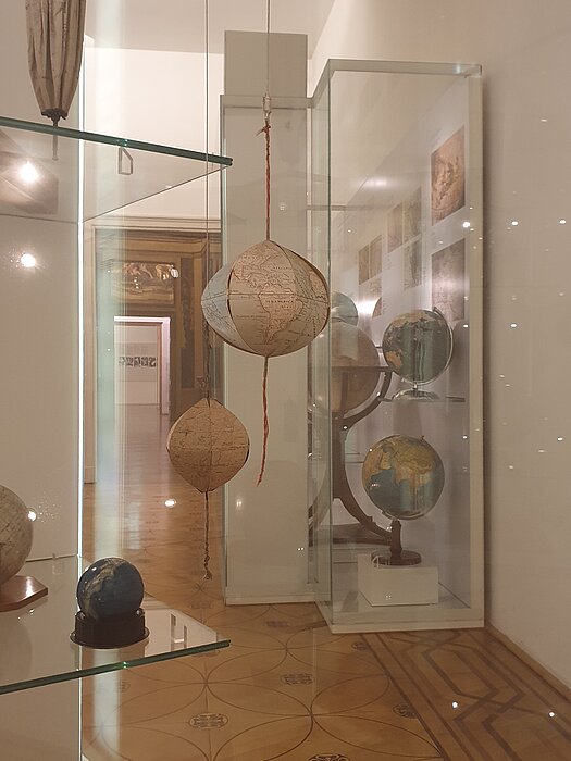Faltgloben ausgestellt in einer Glasvitrine. 
