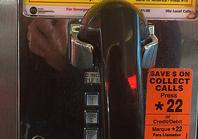Aufnahme eines Telefonzellen-Telefons, mit div. Aufklebern an der Rückwand: "Free Calls" "Save $ on collect calls" ...