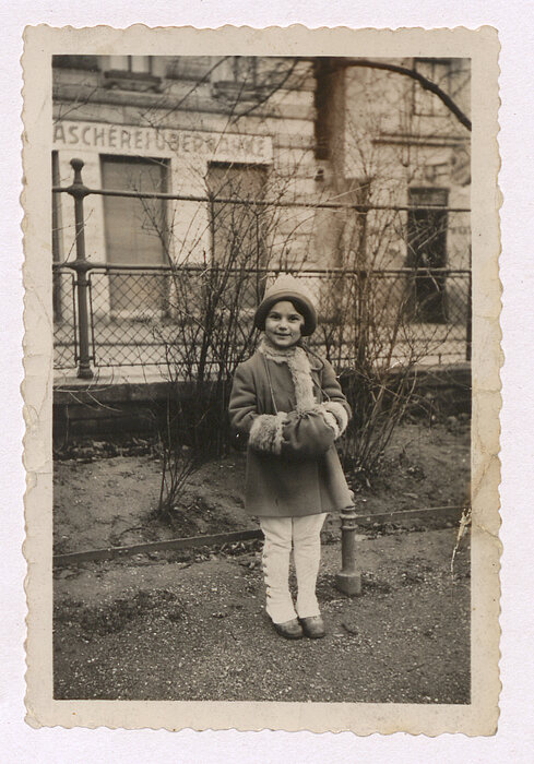 black and white photo of a girl standing in a park, wearing winter clothes