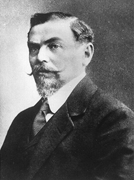 Porträtfoto in schwarz-weiß, Mann mit Schnauzer und Anzug