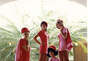 Foto von vier Frauen in pinken Uniformen, die vor einer großen Pflanze posieren.