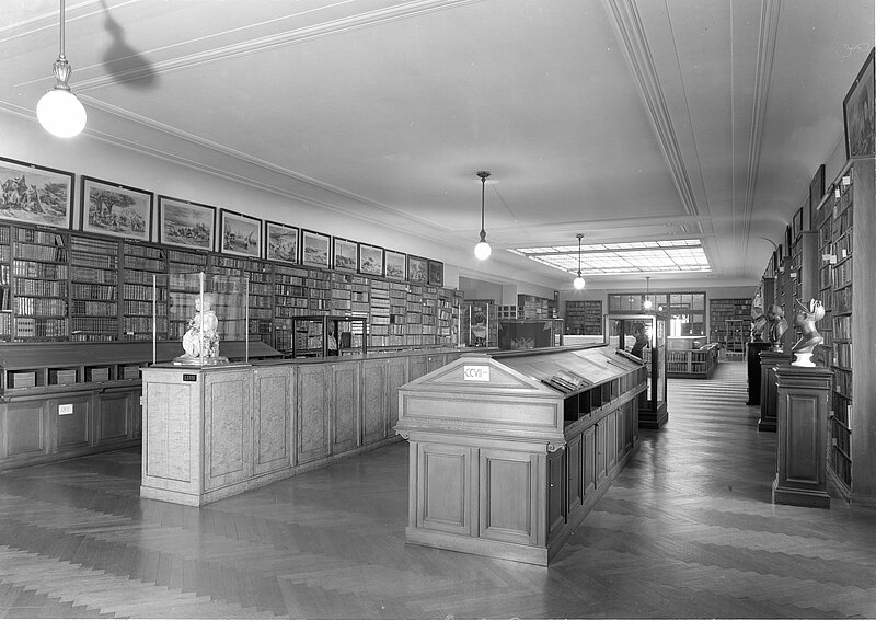Foto von Bibliothek mit Büsten, Gemälden und Vitrinen, schwarz-weiß