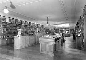 Foto von Bibliothek mit Büsten, Gemälden und Vitrinen, schwarz-weiß