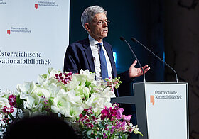 Person im Anzug am Rednerpult.