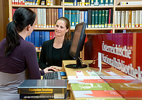 Zwei Personen unterhalten sich vor einem Bücherregal