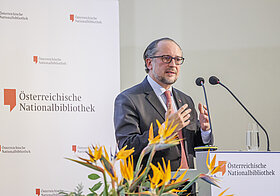 Person spricht in Mikro auf Bühne.