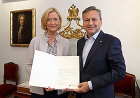 Zwei Personen posieren mit Urkunde.