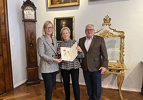 Drei Personen halten eine Urkunde.