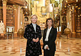 Zwei Personen vor dem goldenen Porträt von Beethoven im Prunksaal.