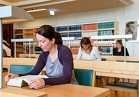 Mehrere Personen sitzen an Tischen und lesen