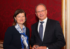 Zwei Personen vor roter Tapetenwand