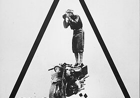 Werbetafel zeigt den Fotografen auf seinem wichtigsten Hilfsmittel, dem Motorrad