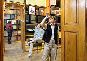 Personen in einem Museum mit alten Bücherregalen
