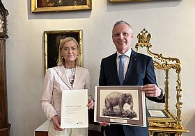Zwei Personen halten eine Urkunde und ein Elefantenbild.