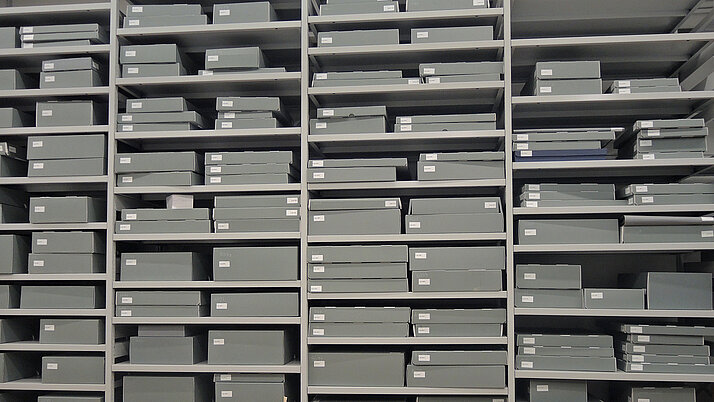 In einem Regal liegt eine Vielzahl Handschriften in Archivboxen.