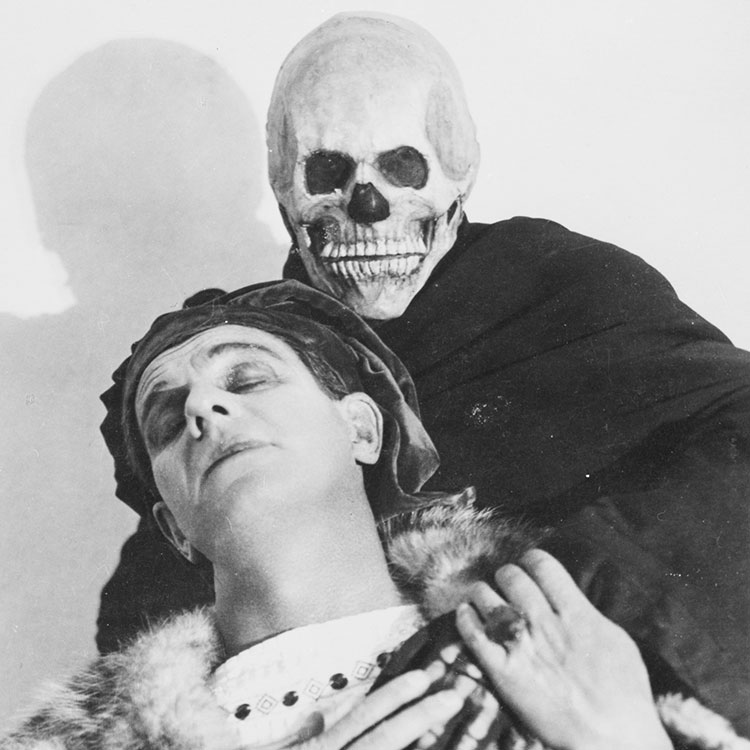 Ein Mann wird von einem anderen Mann mit Totenkopfmaske gehalten, schwarz-weiß