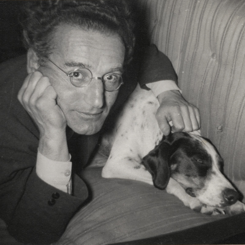 Mann mit Hund auf Couch, Kopf aufgestützt, blickt in die Kamera, schwarz-weiß